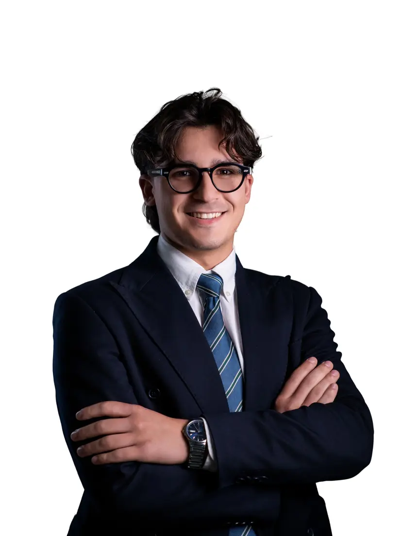 Ritratto professionale di un ragazzo in abito blu e occhiali, a braccia conserte