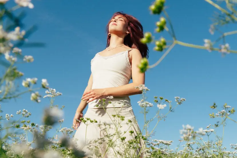 Ragazza dai capelli rossi in abito bianco tra i fiori di campo
