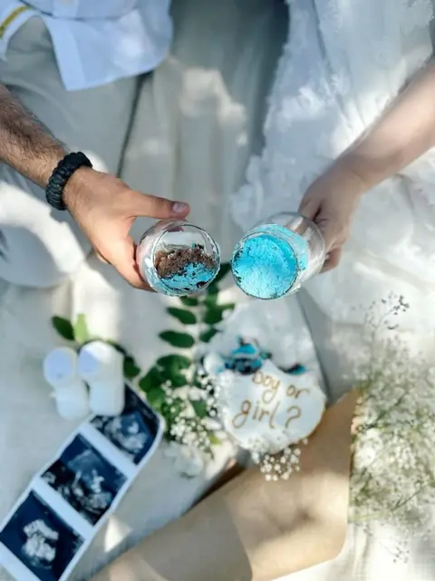 Coppia con barattoli di polvere azzurra durante un gender reveal