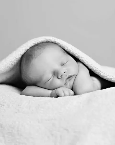 Neonato che dorme avvolto in una coperta bianca
